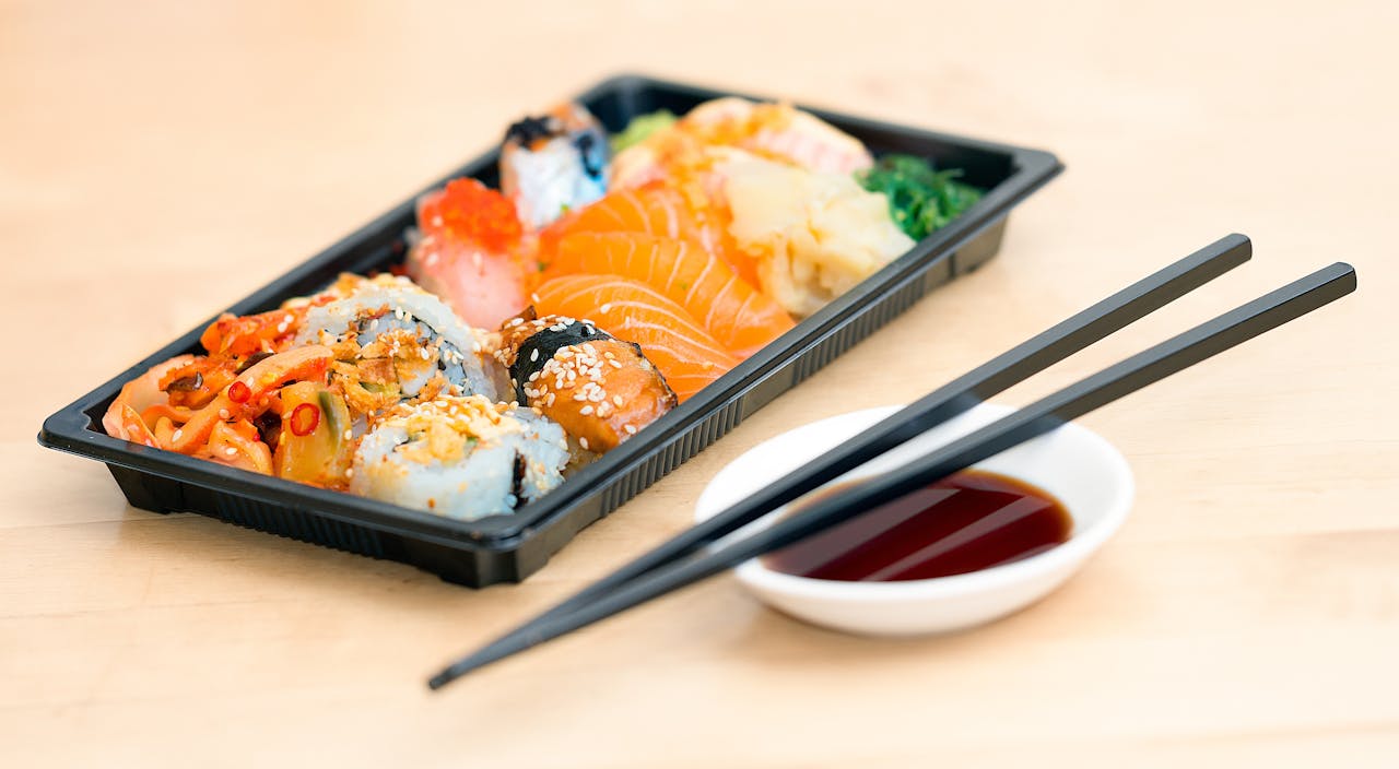 A mouthwatering assortment of sushi rolls and sashimi served with soy sauce and chopsticks.