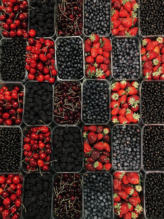 Top view of assorted fresh berries neatly packed in containers, showcasing vibrant colors.